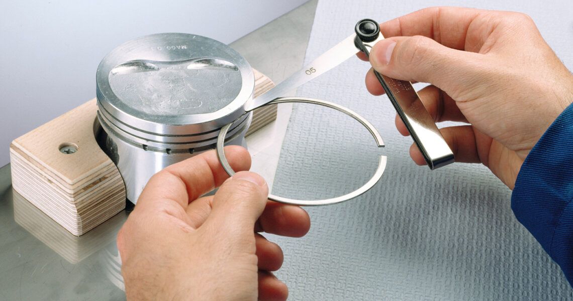 Ringhöhenspiel prüfen ein Mechaniker prüft das Ringhöhenspiel an einem gebrauchten Kolben in ausgebautem Zustand